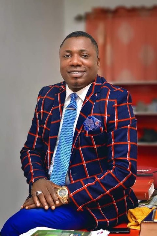 A minister seated in a checked blazer